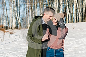 Beautiful young couple in love walks and laughs in a park on a clear sunny winter day