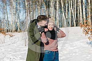 Beautiful young couple in love walks and laughs in a park on a clear sunny winter day