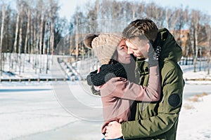 Beautiful young couple in love in a winter park on a clear sunny day. The guy seeks to kiss his beloved girl