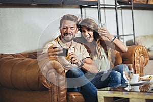 Young couple is making selfie using a smartphone and smiling while sitting in the cafe