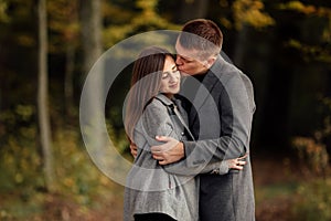 Beautiful young couple man and woman in love. Boyfriend and girlfriend hugging together in park on autumn sunny day. Tenderness