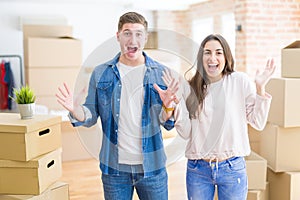 Beautiful young couple moving to a new house celebrating crazy and amazed for success with arms raised and open eyes screaming