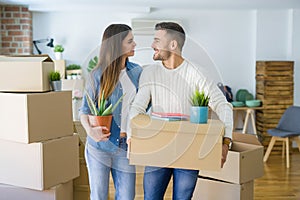 Beautiful young couple moving to a new house, smiling happy holding cardboard boxes at new apartment