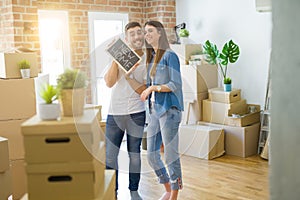 Beautiful young couple moving to a new house, smiling very happy holding blackboard with new home text