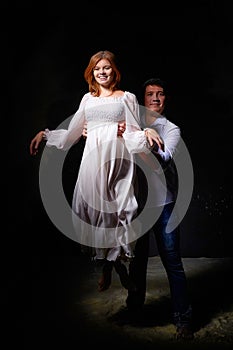 Beautiful young couple during a photo shoot in a dark Studio. A young man and a girl pose together on a black background