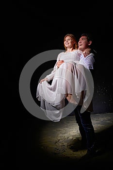 Beautiful young couple during a photo shoot in a dark Studio. A young man and a girl pose together on a black background