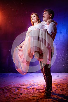 Beautiful young couple during a photo shoot in a dark Studio. A young man and a girl pose together on a black background