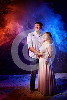 Beautiful young couple during a photo shoot with flour in a dark Studio. A young man and a girl pose together on a black