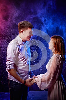 Beautiful young couple during a photo shoot with flour in a dark Studio. A young man and a girl pose together on a black