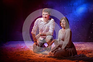 Beautiful young couple during a photo shoot with flour in a dark Studio. A young man and a girl pose together on a black