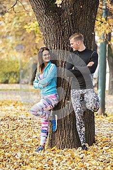 Beautiful young couple recumbent to tree together in the park.
