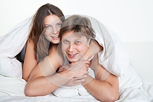 Beautiful young couple relaxing in bed at home