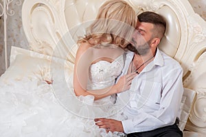 Beautiful young couple resting in bed. The bride and groom in bed. A young family on their wedding day. Wedding Dress