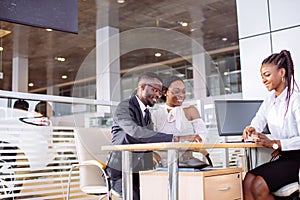 African couple getting car key from dealer in showroom and signing contract