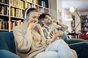 Young couple sitting in the cafe, drinking coffee and listening to music with smart phone