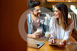 Beautiful young couple sitting in cafe, having fun with tablet. Students during break in the cafe.