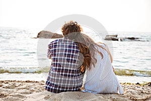 Beautiful young couple sitting together on the beach