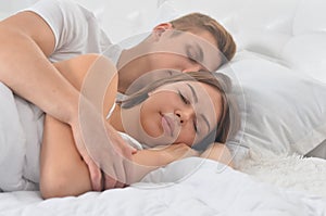 Beautiful young couple sleeping on soft bed in morning