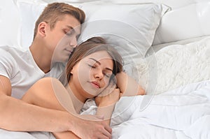Beautiful young couple sleeping on soft bed in morning