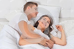 Beautiful young couple on soft bed in morning