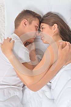 Beautiful young couple on soft bed in morning