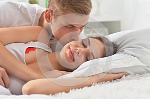 Beautiful young couple on soft bed in morning