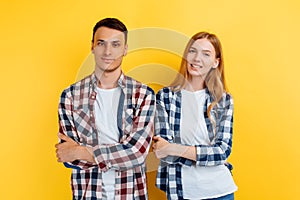 Beautiful young couple of students, man and woman with laptop on yellow background