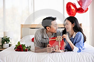 Beautiful young couple surprise with rose and gift in bedroom,Valentine's Day concept