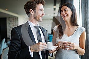 Beautiful young couple talking to each other and smiling while enjoying coffee