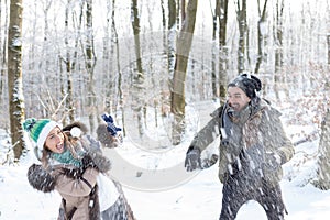 Beautiful young couple throwing snowballs at each other