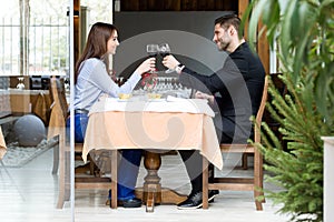 Beautiful young couple toasting wine glasses in the restaurant.