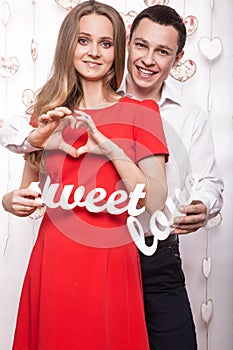Beautiful young couple with words Sweet love showing the form of heart hands. Valentine's Day.