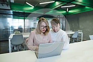 Beautiful young couple working with a laptop in a stylish, modern office