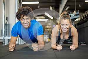 Beautiful young couple working out at the gym doing planks