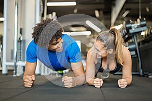 Beautiful young couple working out at the gym doing planks