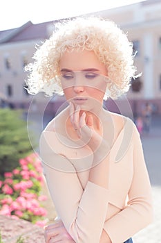 Beautiful young curly blond girl outdoors in the sun at sunset on a bright day