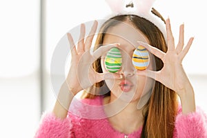 A beautiful young cute black long hair Asian woman covered her eyes with painted easter eggs