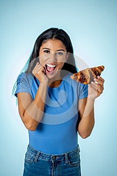 Beautiful young cute and happy latin woman in casual clothes holding big delicious chocolate croissant looking with temptation