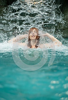 beautiful young cute sexy sensual redhead woman, enjoying the splashing water of the waterfall in the Spa Wellness pool