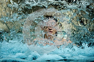 Beautiful young cute sexy woman behind the curtain of the pattering waterfall, enjoying the splashing water in the spa wellness