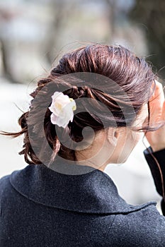 Beautiful young dark haired woman with creative plait hairdo with a flower