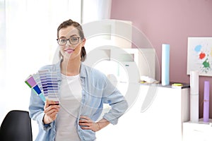 Beautiful young designer with color palette in office