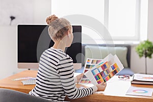 Beautiful young designer working with color palette in office