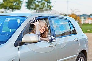 Beautiful young driver looking out of the car holding key