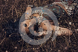 beautiful young eastern girl in ethnical jewelry lying on a grass on a field photo