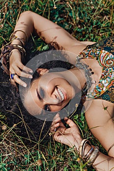 beautiful young eastern girl in ethnical jewelry lying on a grass on a field