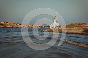 Beautiful young elegant pregnant blond woman in a blue hat walks on the beach, seashore at sunset. sea. Motherhood.