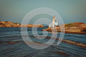 Beautiful young elegant pregnant blond woman in a blue hat walks on the beach, seashore at sunset. sea. Motherhood.