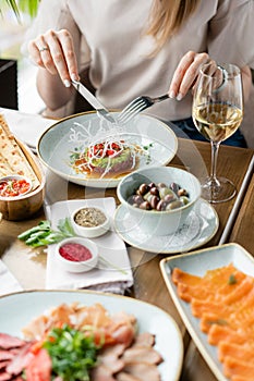 Beautiful young elegant woman in the restaurant with a wine glass. Dinner and a variety of dishes on the table. Italian