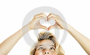 Beautiful young emotional girl showing heart from hands on an isolated background. The concept of love and health
